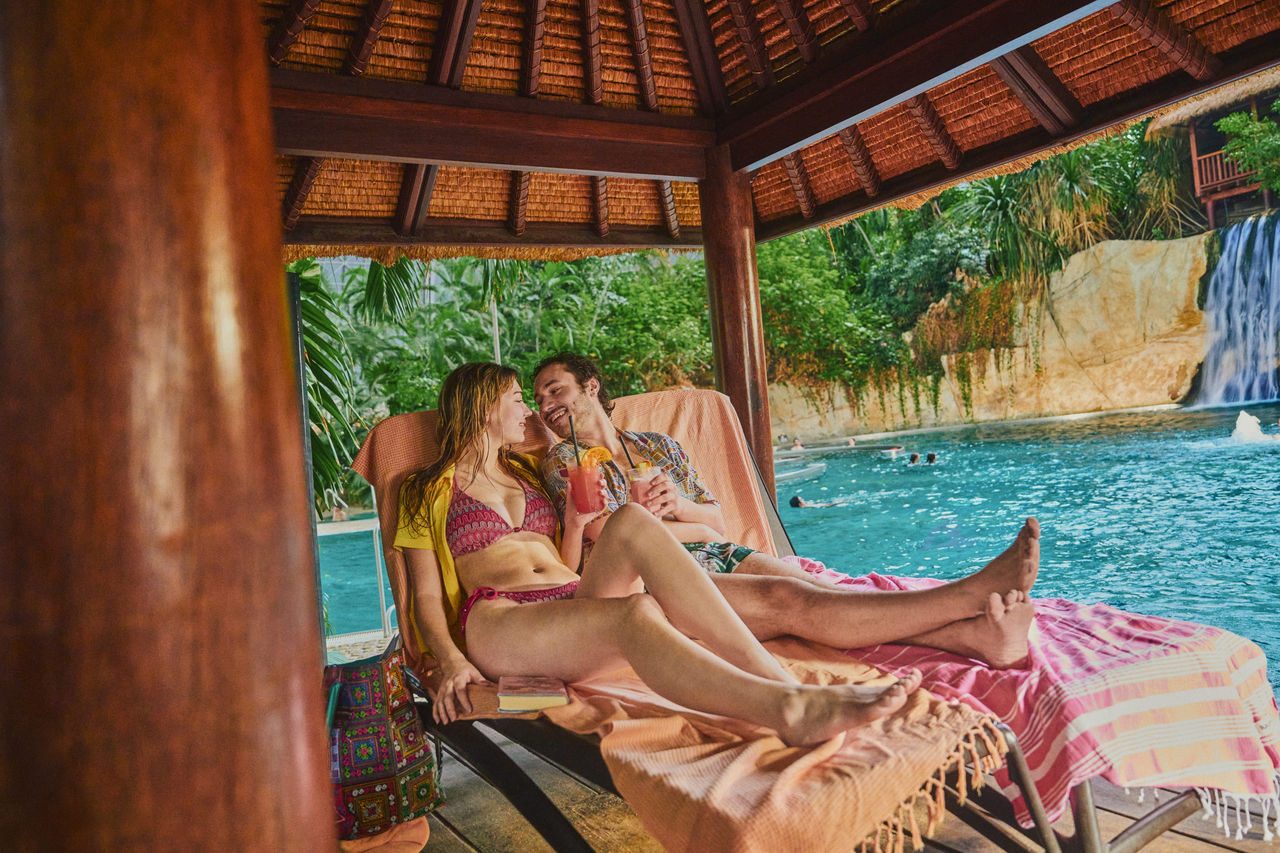 Pärchen sitzt an der Lagune auf zwei Liegen und schaut sich romantisch an.