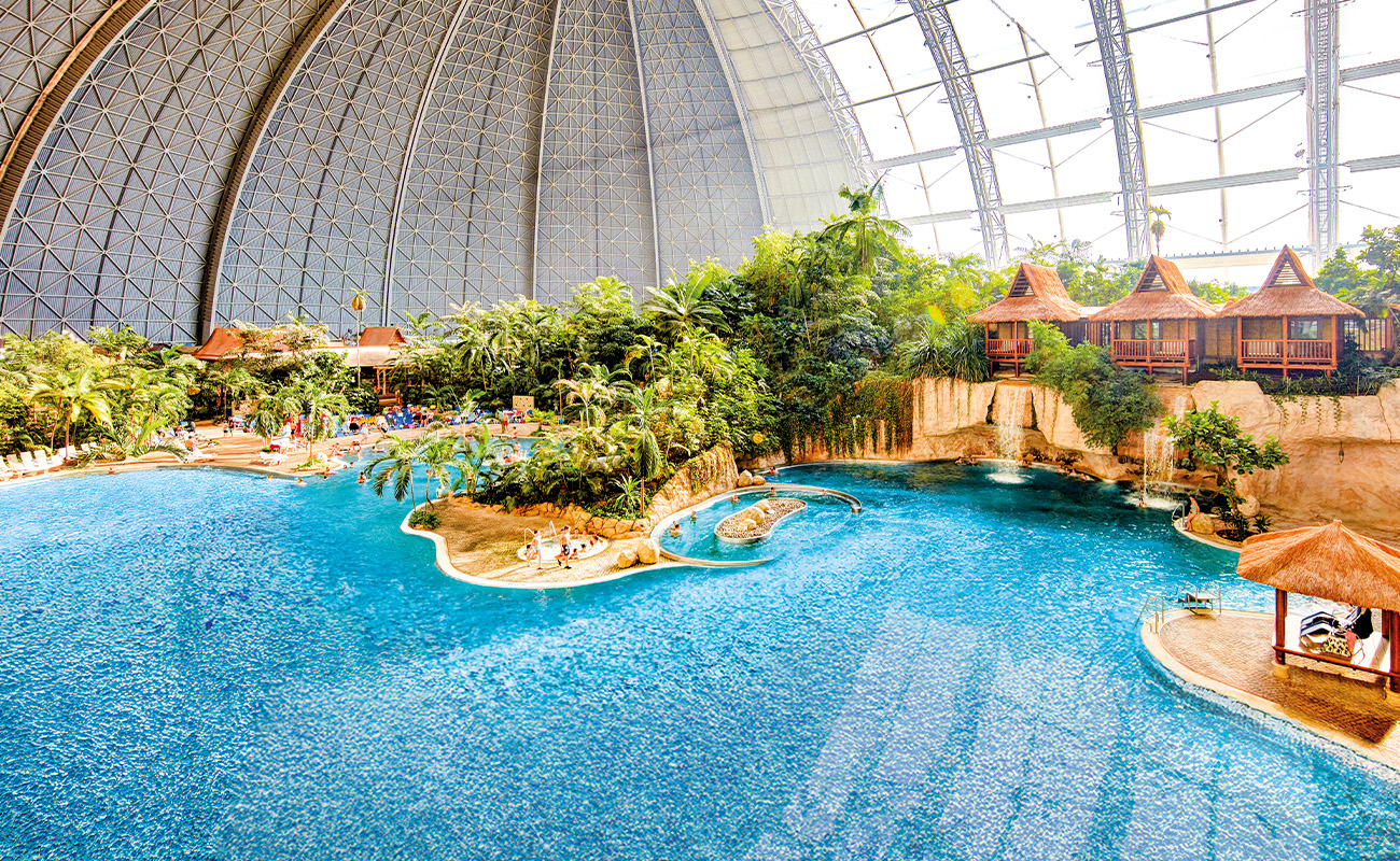 Indoor pool lagoon with tropical vegetation and the Waterfall Suites under a dome.