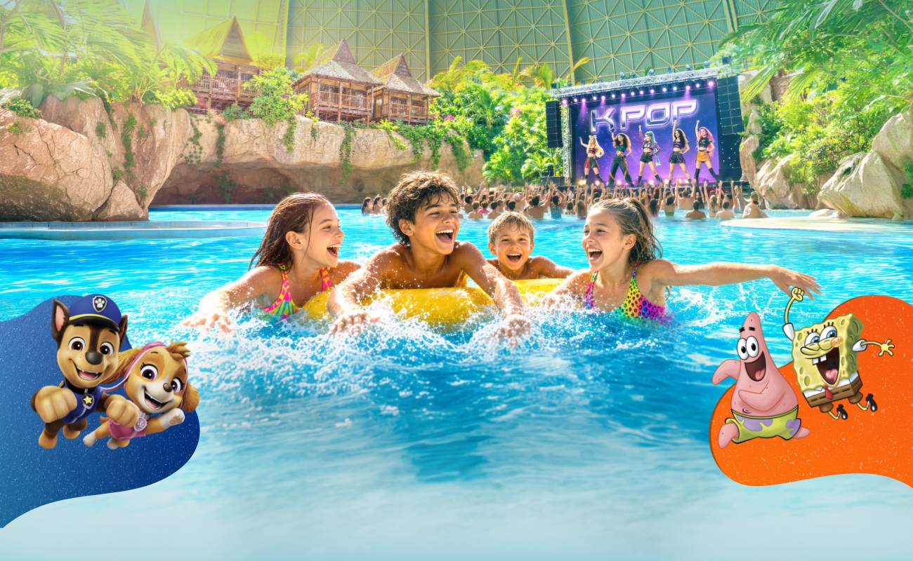 Das Becken 'Lagune' im Tropical Islands aus der Vogelperspektive, im Hintergrund Palmen und Junior-Suiten über einem Wasserfall.