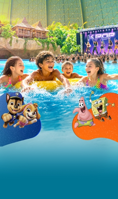 Das Becken 'Lagune' im Tropical Islands aus der Vogelperspektive, im Hintergrund Palmen und Junior-Suiten über einem Wasserfall.