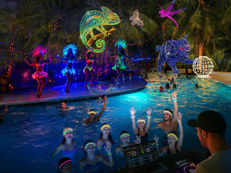 People with glowing accessories celebrate in the water, with a DJ in the foreground. In the background, samba dancers in bright outfits and glowing animal figures.
