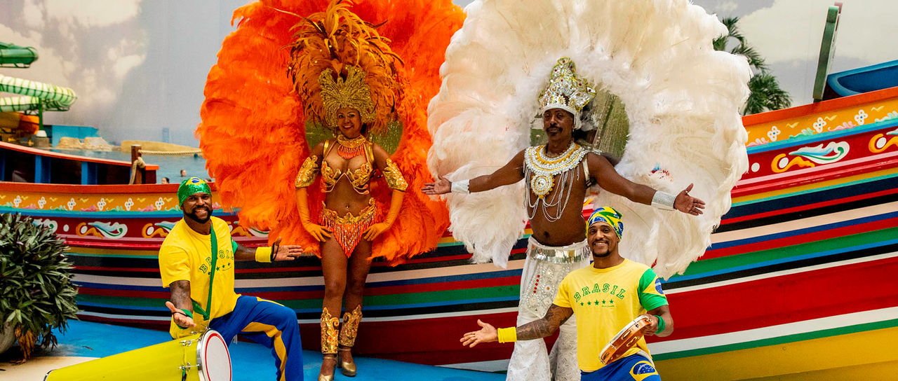 Dancers in samba outfits and dancers with drums dressed in Brazilian colors pose on the South Sea stage at Tropical Islands