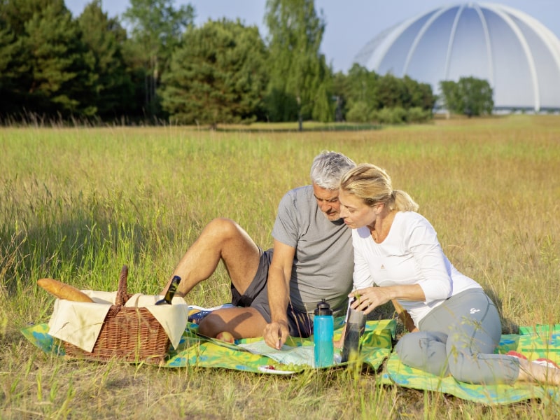 Pärchen beim Picknick in der Heidelandschaft, im Hintergrund die Tropical Islands Halle 