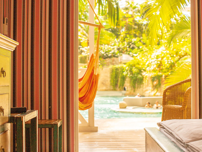 Accommodation with a view of a water pool and a terrace with a hammock in front of tropical plants