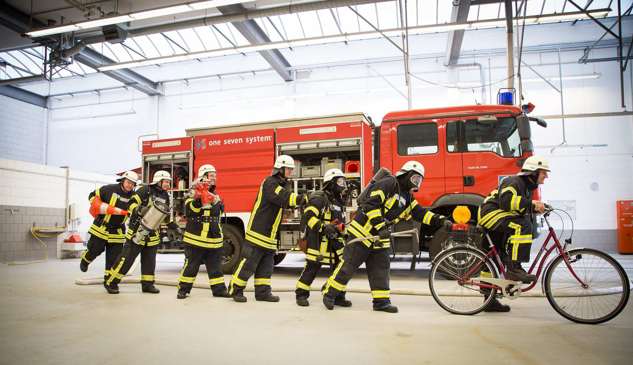 Sieben Feuerwehrmänner in Uniformen in lustiger Pose