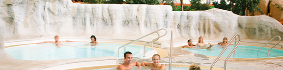 Wellnessbereich mit Pool, entspannte Gäste im Wasser, Felsdeko und Handläufen