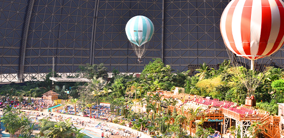 Ein tropisches Erlebnisbad unter einer Kuppel mit Pool, Pflanzen und zwei Ballons..