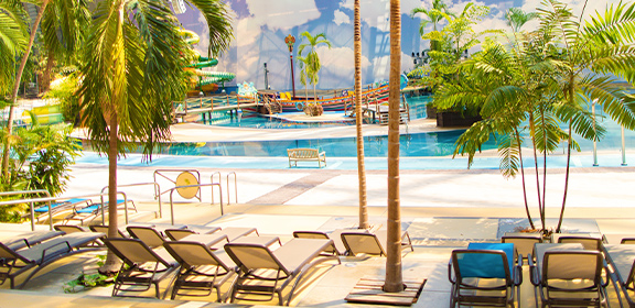 Tropischer Indoor-Poolbereich der Südsee mit Liegestühlen, Palmen und Sandstrand.