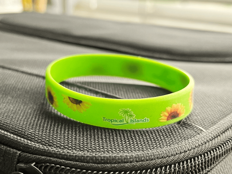 Grünes Armband mit Sonnenblumen und Tropical Islands Schriftzug auf schwarzer Oberfläche