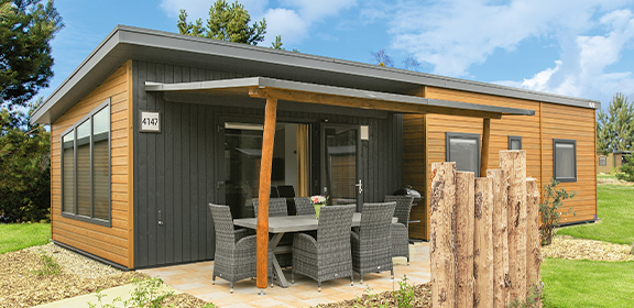 Modernes Sunrise Home mit Holz- und Dunkelgraufassade, großen Fenstern und möblierter Terrasse