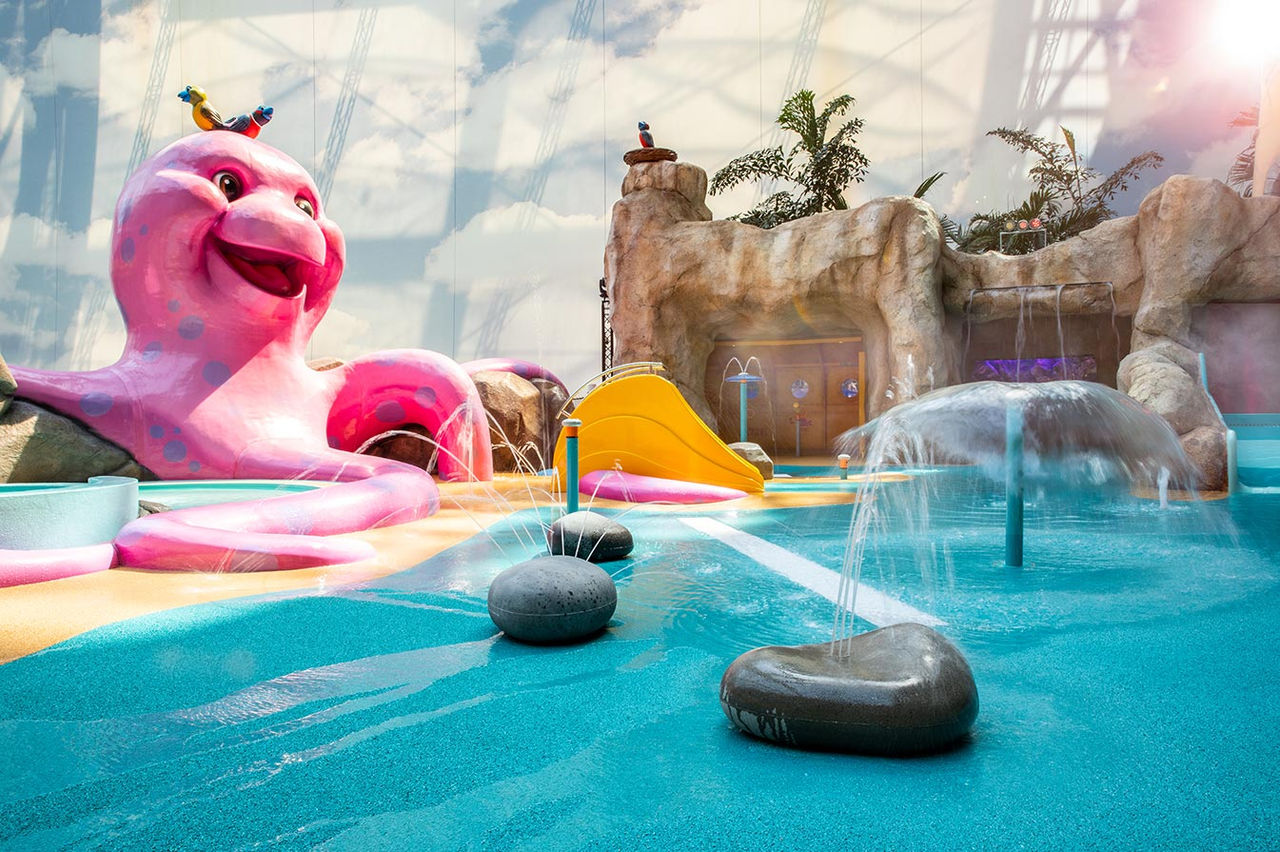 Indoor-Pool Lagune mit tropischer Vegetation und den Waterfall Suites unter einer Kuppel.