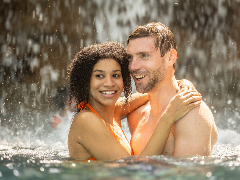 Lächelndes Pärchen im Lagunen-Becken des Tropical Islands, im Hintergrund der Wasserfall.