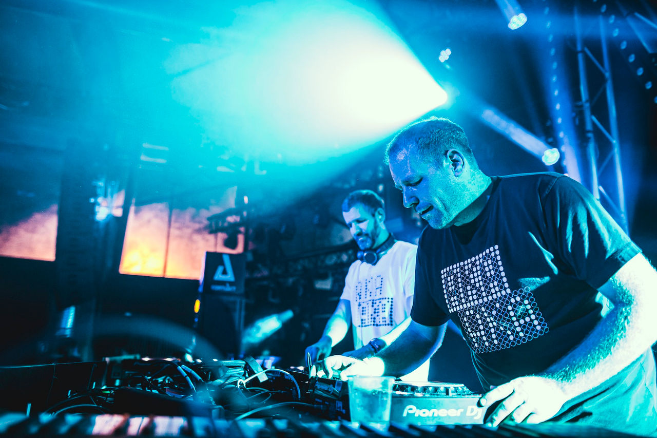 Zwei Männer, die Berliner DJs AKA AKA, stehen an den Decks in einem Club.
