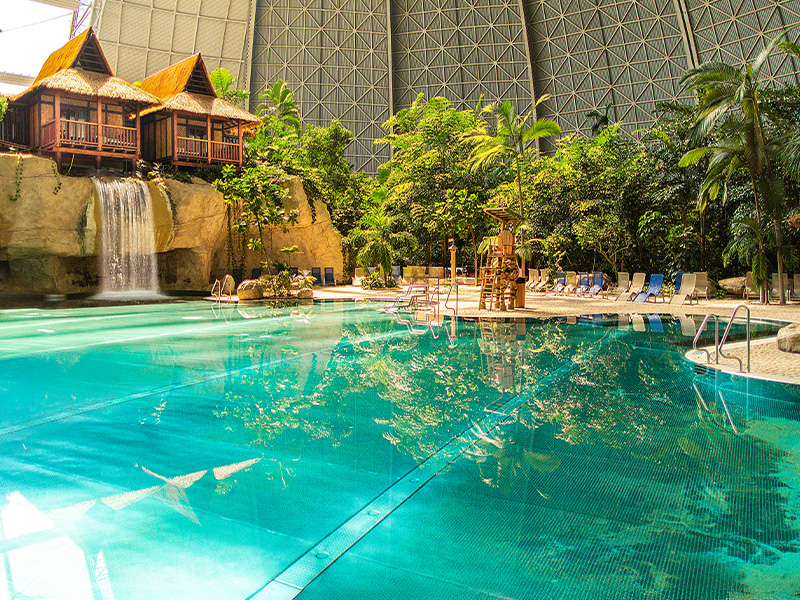 Der Pool "Lagune" in der Tropical Islands Halle umgeben von Regenwald, links ein Wasserfall und darüber Junior Suiten