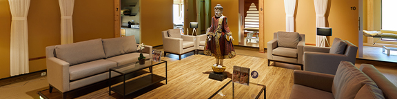 Wellness area with several sofas, coffee table, statue in the center and decorative elements on wooden floor