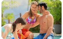 Three people in swimwear on a sandy beach in the South Sea.