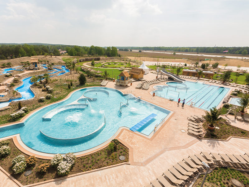 AMAZONIA outdoor area with spacious pools, water slides, sunbathing areas and green surroundings in sunny weather.