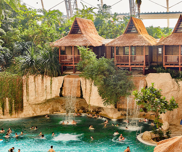 Tropical lagoon with waterfalls, palm trees and huts over the water.