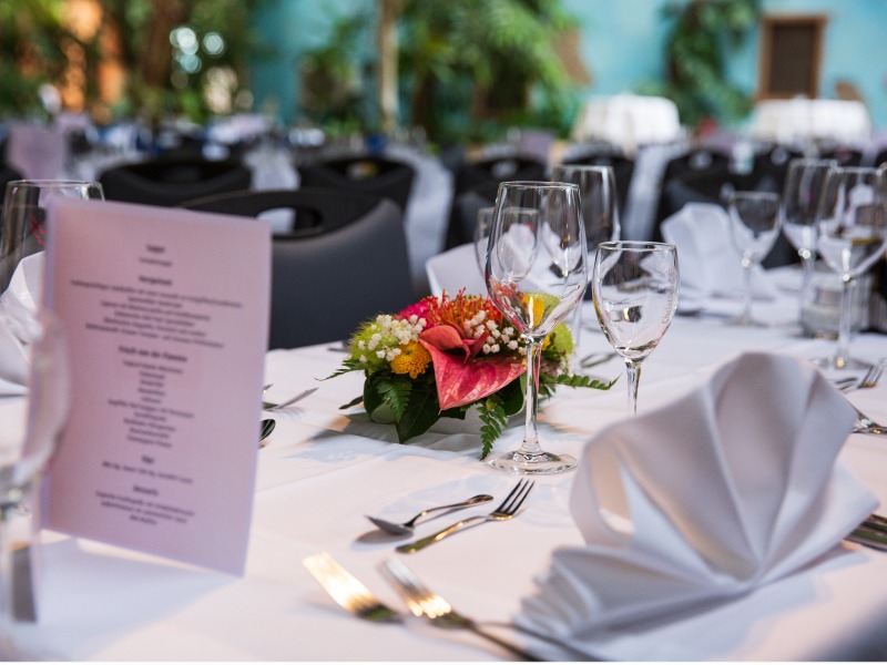 Table set with folded white napkins, menu, and wine glasses.
