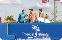 Four people stand with bodyboards behind a blue barrier with the “Tropical Islands” logo.