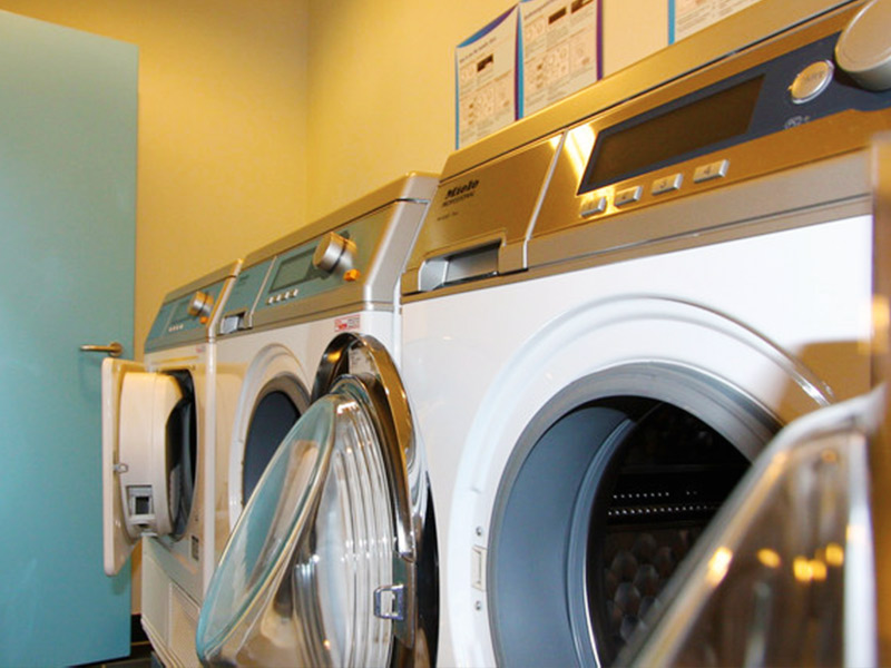 Laundry room with white front-loading washing machines and dryers, some with open doors.
