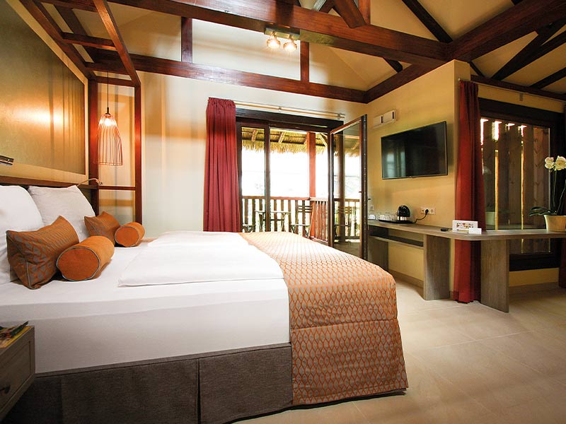 Bright bedroom with large bed, wooden beamed ceiling, desk and access to the balcony.